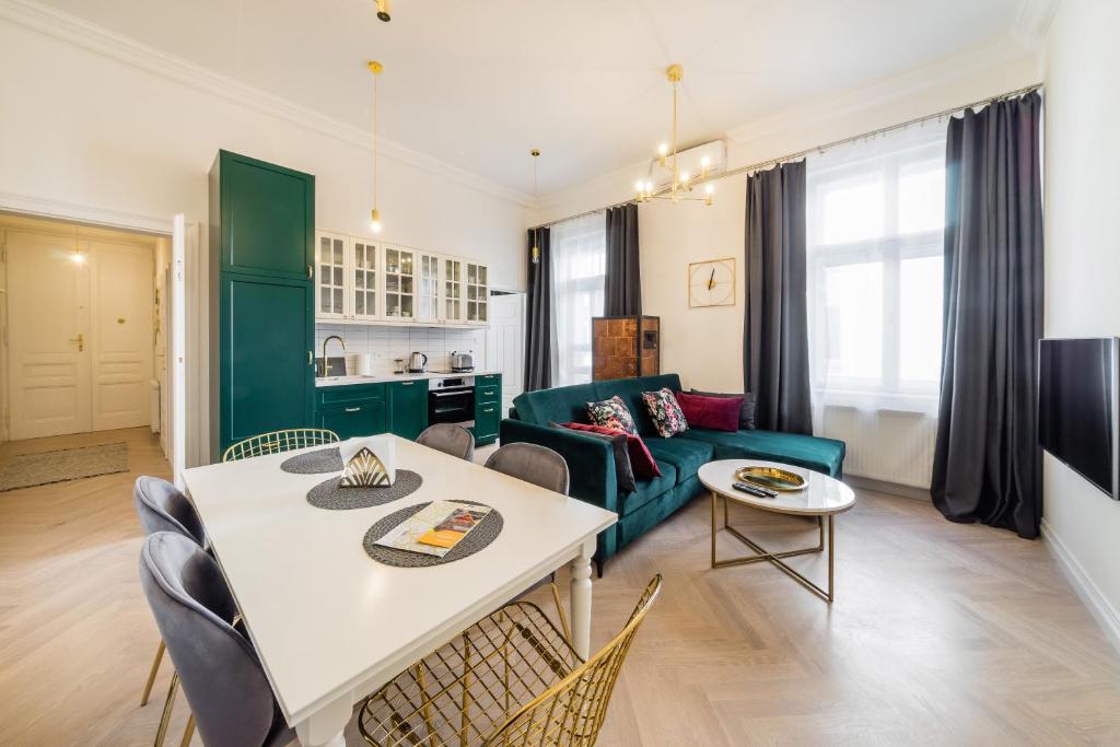 ein Wohnzimmer mit einem Tisch und einem grünen Sofa in der Unterkunft Apartament Deluxe Old Town św. Krzyża WAWELOFTS in Krakau