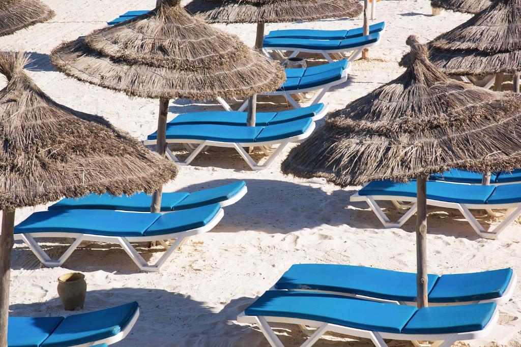 a group of chairs and umbrellas on a beach at AQI Skanes Resort in Monastir