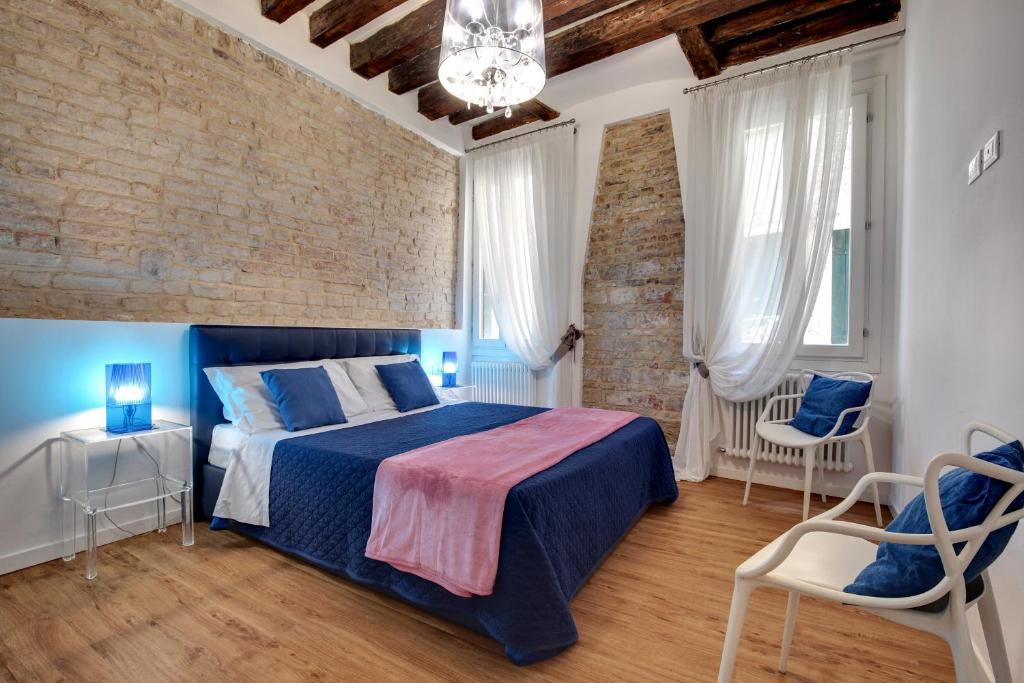 1 dormitorio con 1 cama azul y 2 sillas en Charming Castello Apartments, en Venecia