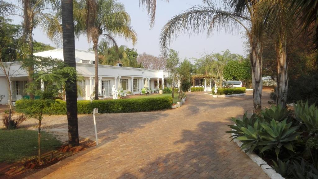 a white house with palm trees in front of it at Heatherdale Guesthouse & Shuttle Services in Pretoria