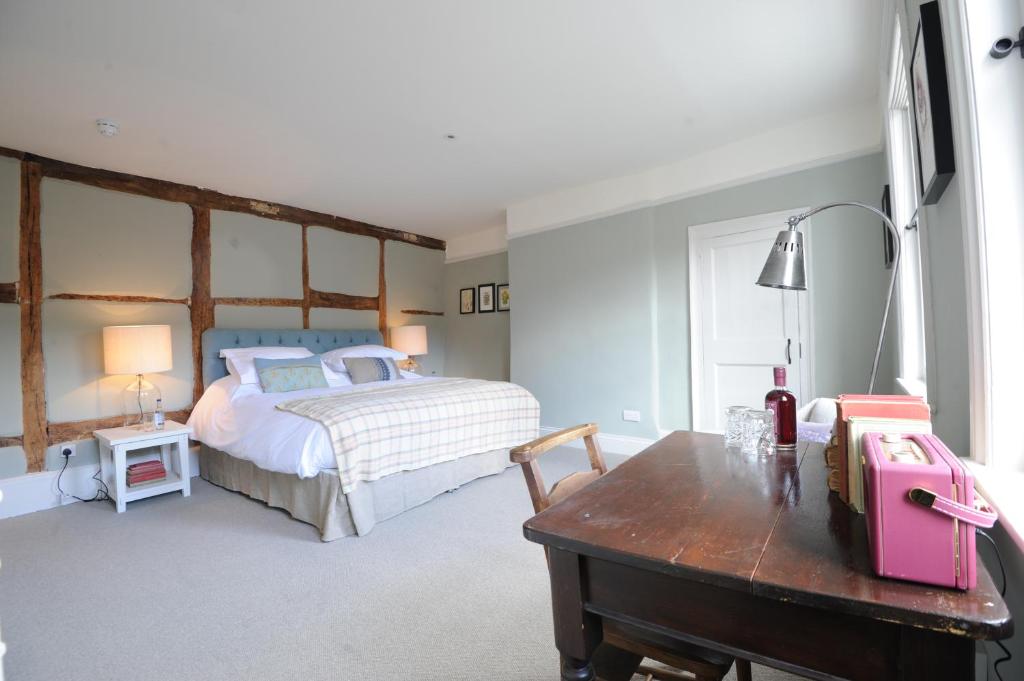 
a bedroom with a bed, chair, desk and a lamp at Bel and The Dragon-Kingsclere in Kingsclere
