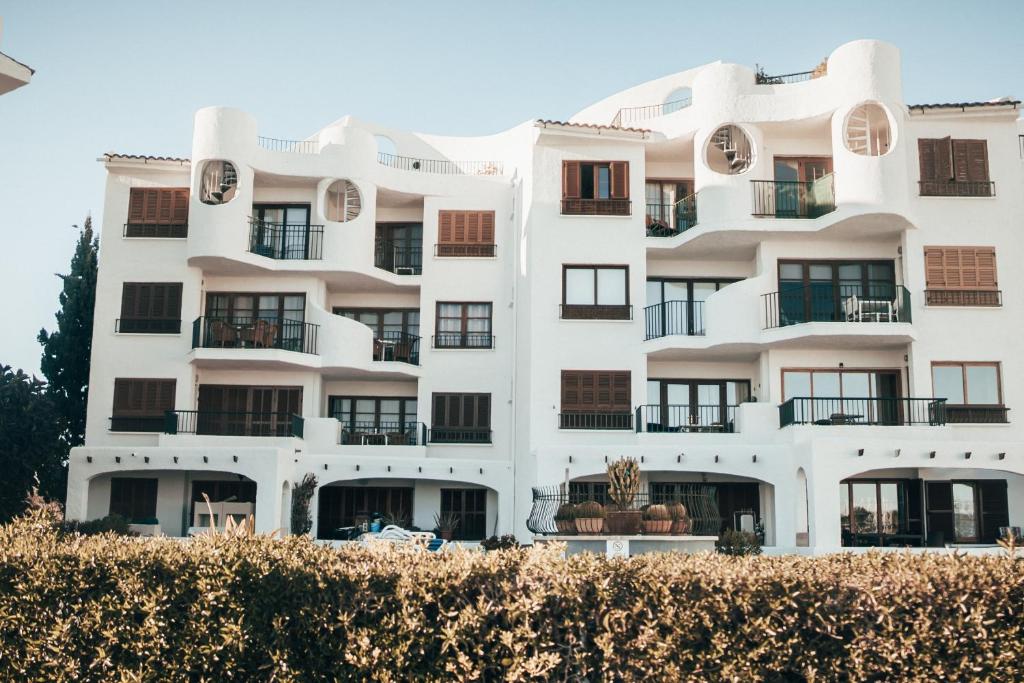 a white apartment building with a hedge in front of it at CARABELA 94 in Alcudia