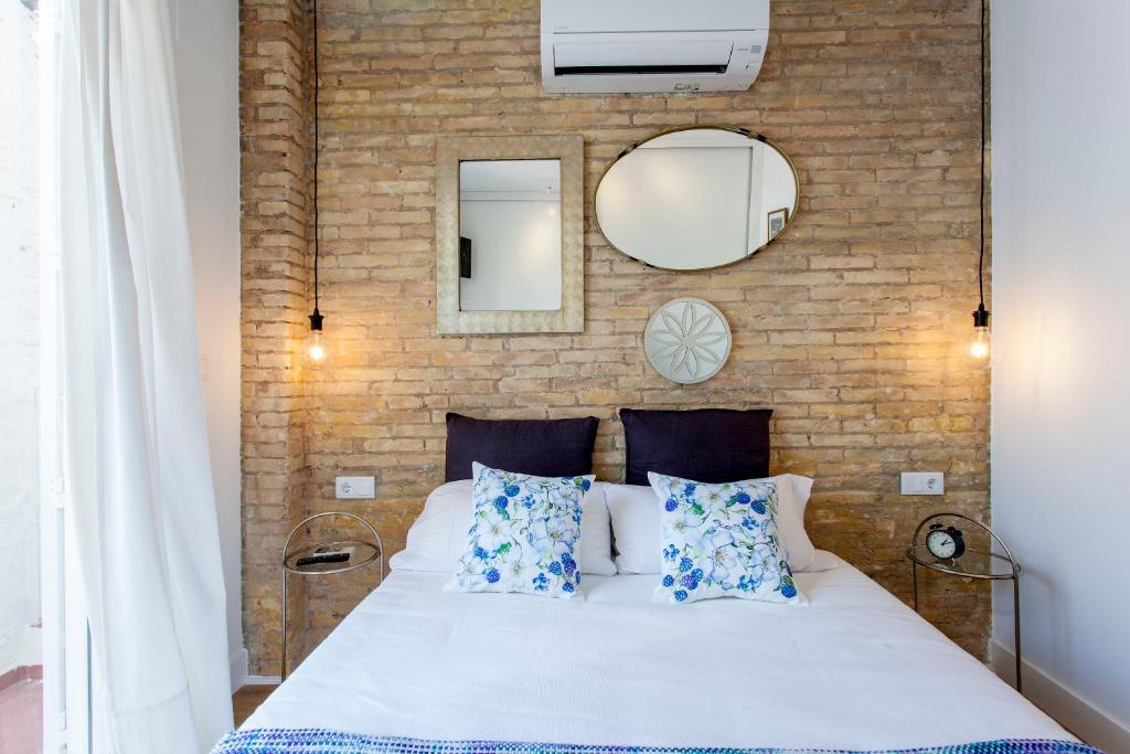 a bedroom with a white bed and a brick wall at ApartUP Rojas Market in Valencia