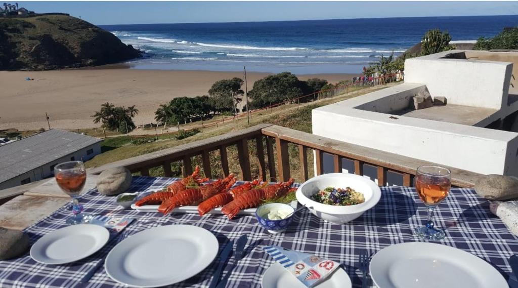a table with plates of food and the beach at Davison Cottage Hole in the Wall in Hole in the Wall