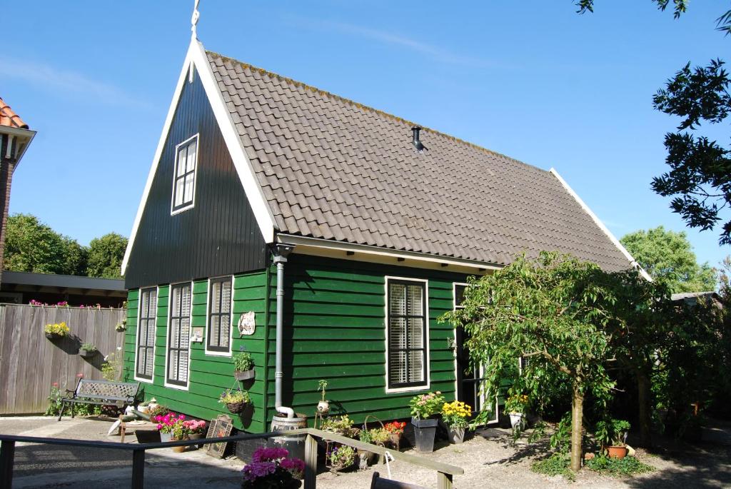 a green house with a black roof at Bed&Brood De StraVerdonk in Graft