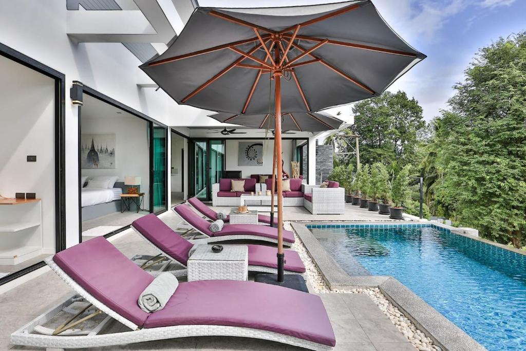an outdoor pool with purple lounge chairs and an umbrella at Villa Hayou, Lamai Koh Samui in Lamai