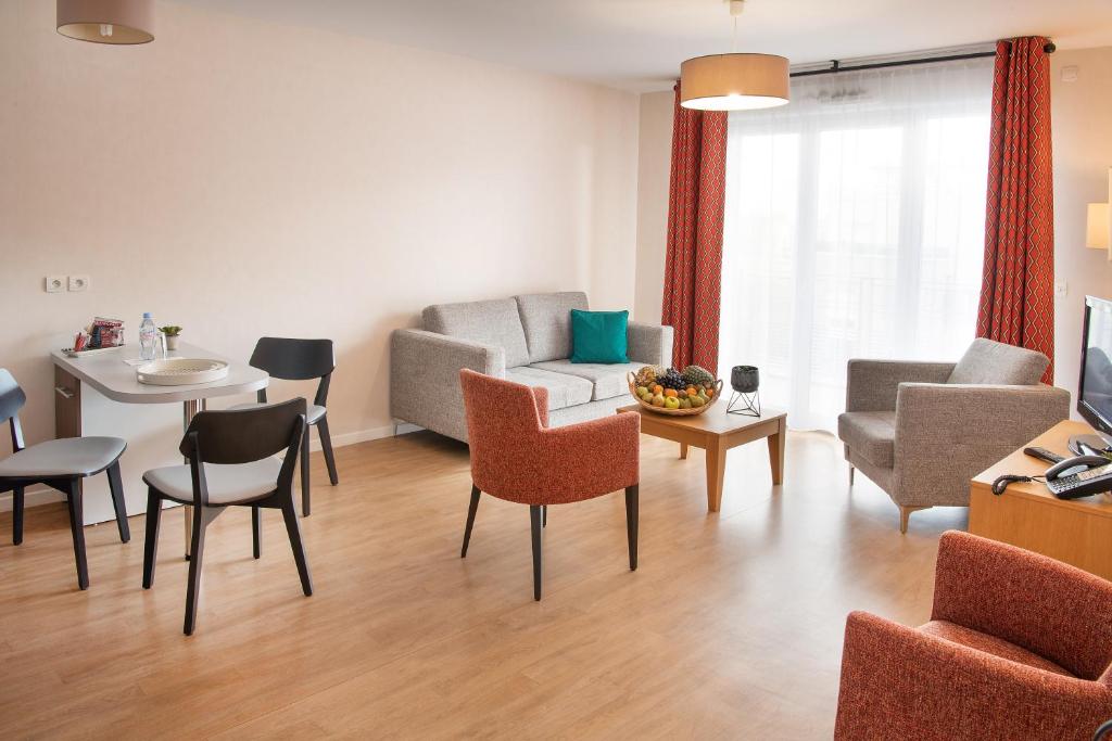 uma sala de estar com um sofá, uma mesa e cadeiras em DOMITYS LES SABLES D'OR em Villeneuve-le-Roi