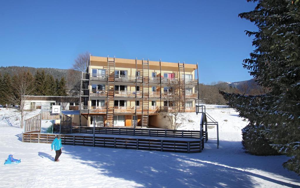 Un bâtiment dans la neige avec des gens devant lui dans l'établissement Résidence Goélia Le Sornin, à Autrans