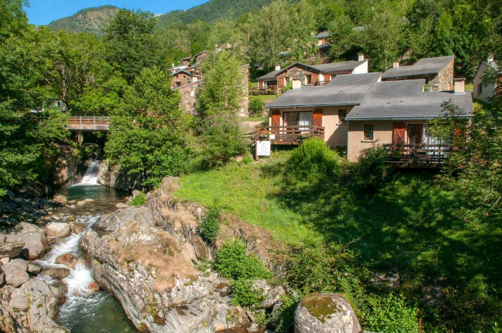 une maison sur une colline à côté d'une rivière dans l'établissement Village vacances de Marc, à Auzat