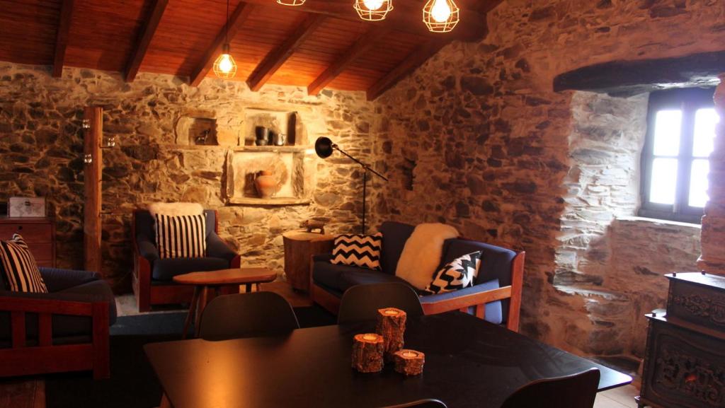 a living room with stone walls and a table and chairs at Casa Javali in Chiqueiro