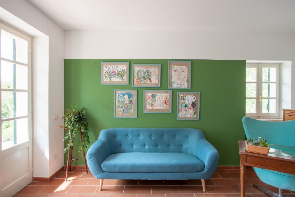 ein blaues Sofa im Wohnzimmer mit grünen Wänden in der Unterkunft AMERICA NEI BOSCHI B&B in Bra