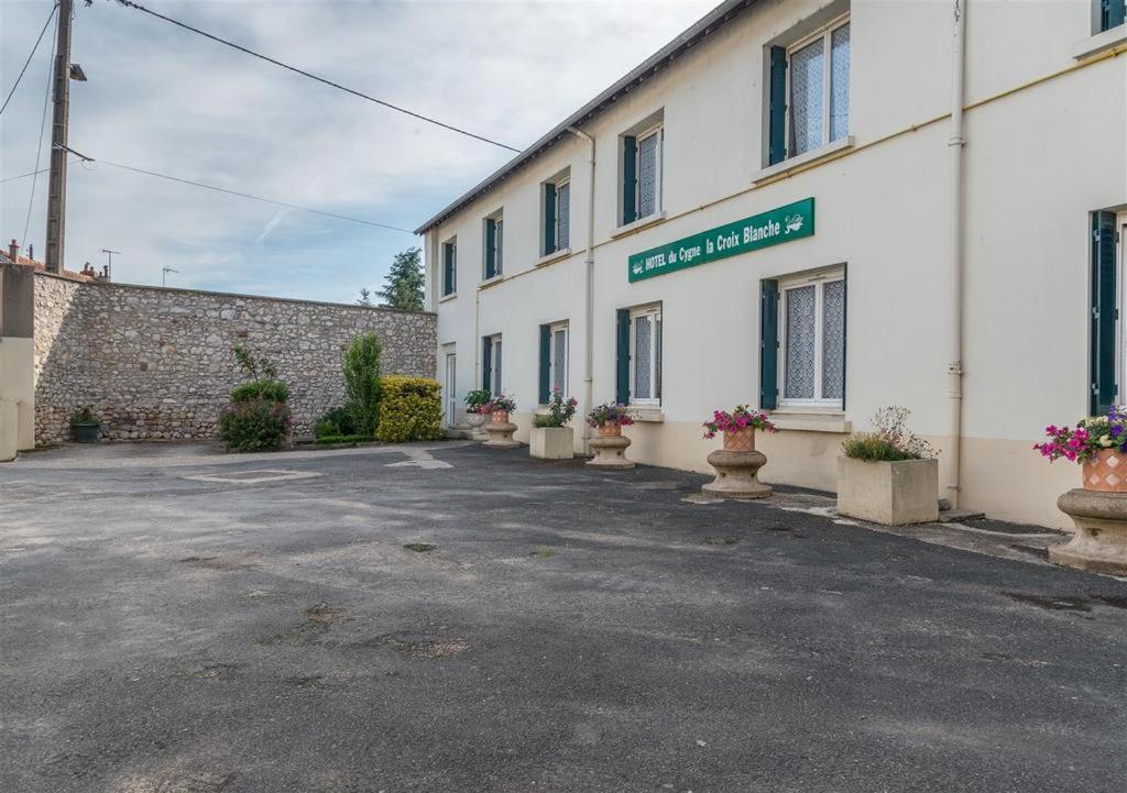 un aparcamiento vacío frente a un edificio en HOTEL DU CYGNE DE LA CROIX BLANCHE, en Lailly-en-Val