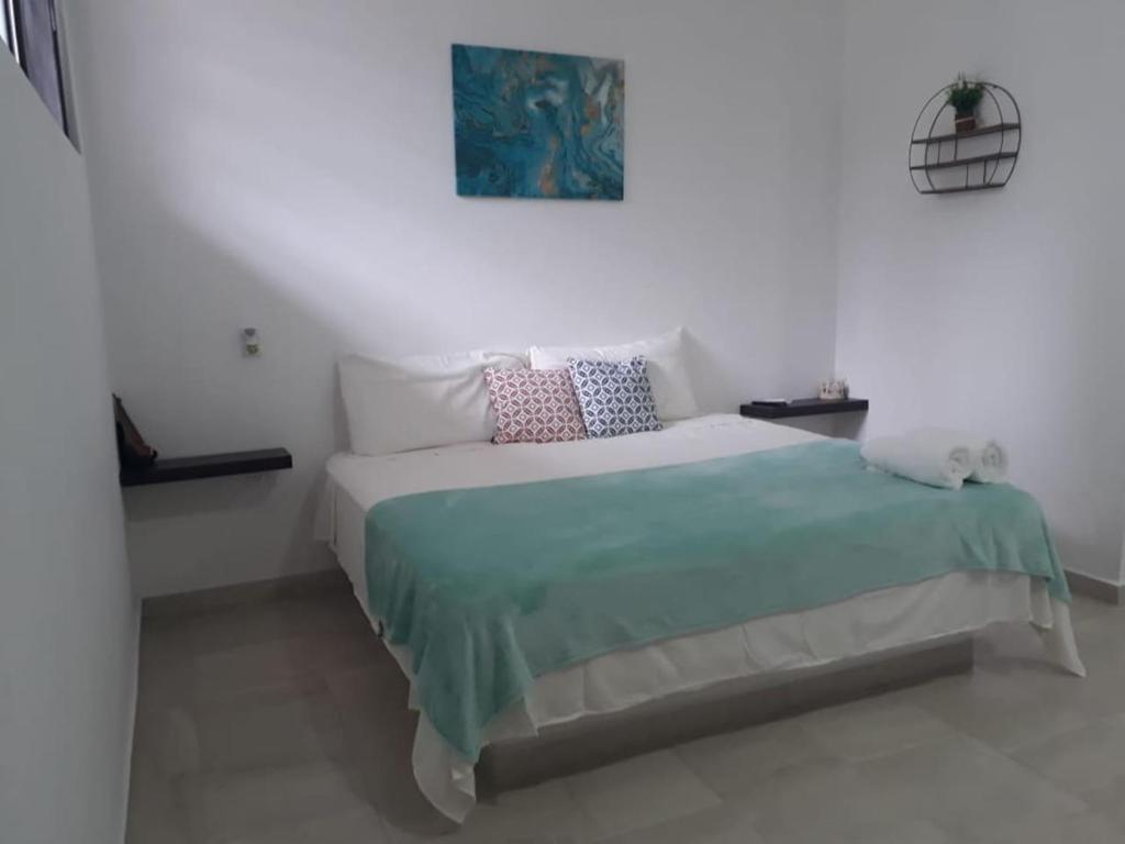 a white bedroom with a bed with a blue blanket at Estudio en Cancún centro in Cancún