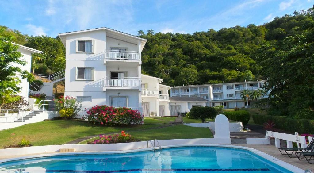 a house with a swimming pool in front of a building at Siesta Hotel in Morne Rouge