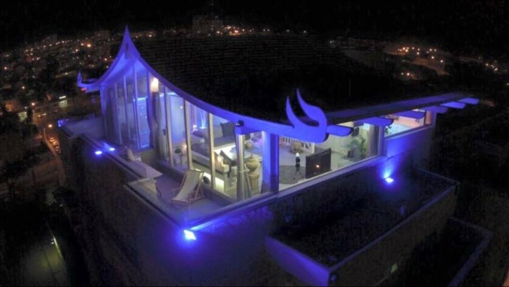 een huis met blauwe lichten er 's nachts op bij Olimpos Eilat in Eilat