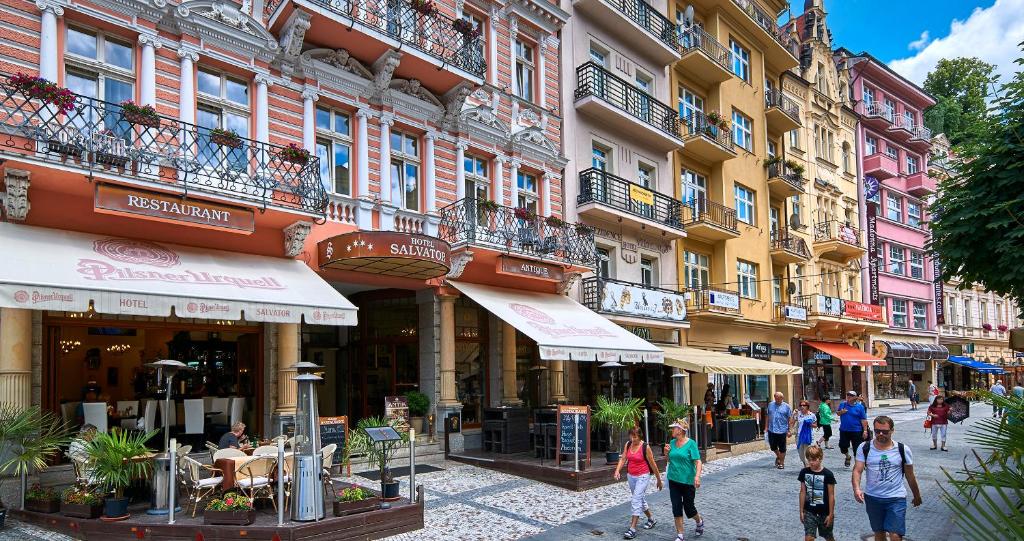 Un groupe de personnes marchant dans une rue avec des bâtiments dans l'établissement Salvator Hotel, à Karlovy Vary