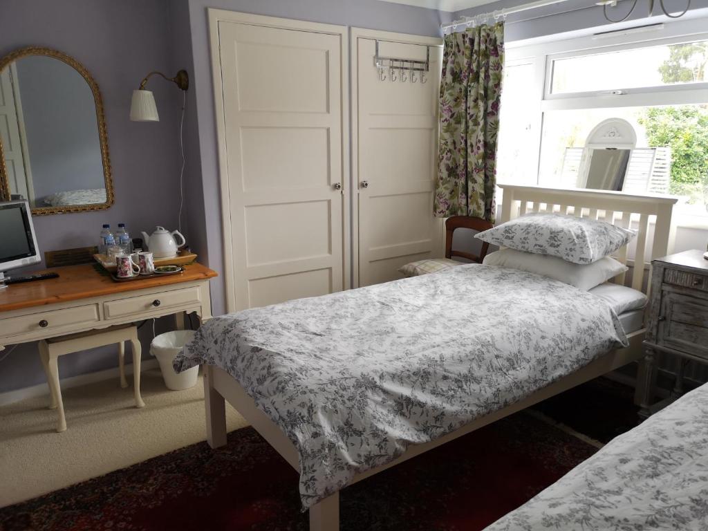 um quarto com 2 camas, uma secretária e um espelho. em UPTHEDOWNS B&B em Sevenoaks