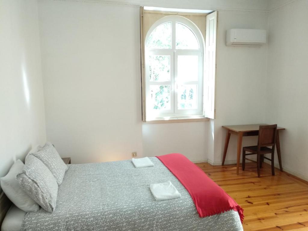 a bedroom with a bed and a window and a table at Carolina M Apartment in front of Metro in Porto