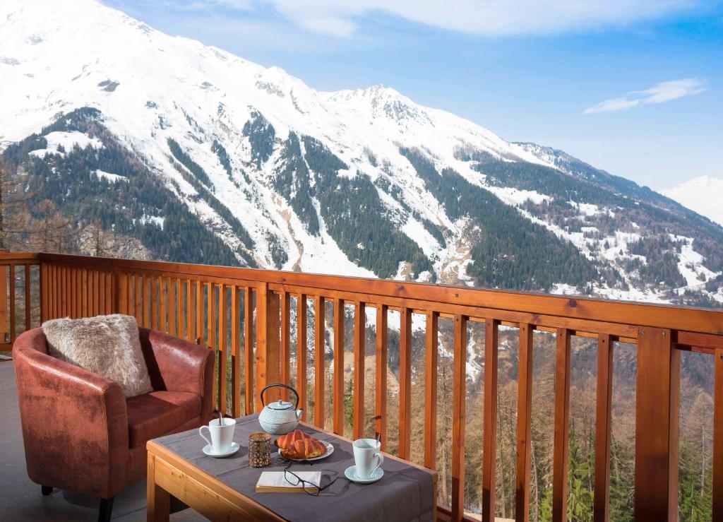 une chaise et une table sur un balcon avec une montagne enneigée dans l'établissement Résidence Club mmv L'Étoile des Cimes ****, à Sainte-Foy-Tarentaise