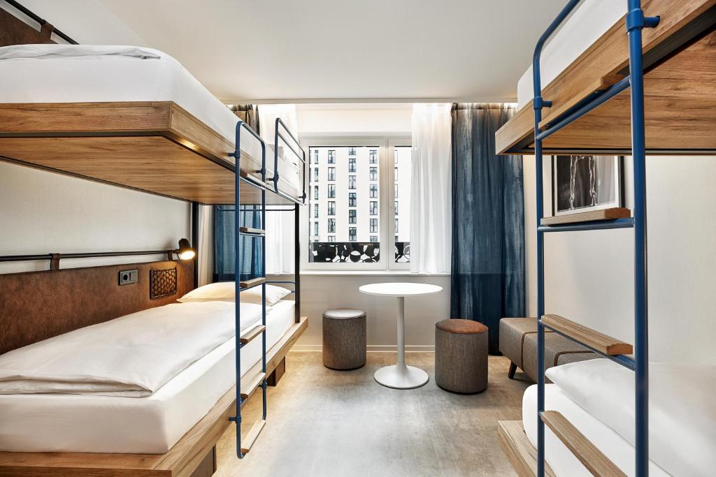 a bedroom with two bunk beds and a desk at H2 Hotel München Olympiapark in Munich