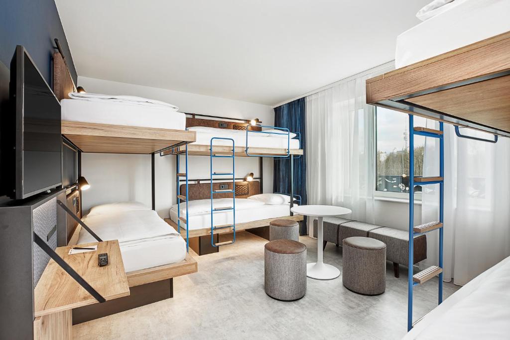 a bedroom with bunk beds and a living room at H2 Hotel München Olympiapark in Munich