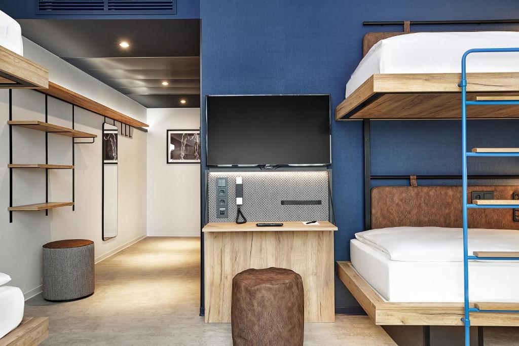 a room with a bunk bed and a desk with a television at H2 Hotel München Olympiapark in Munich