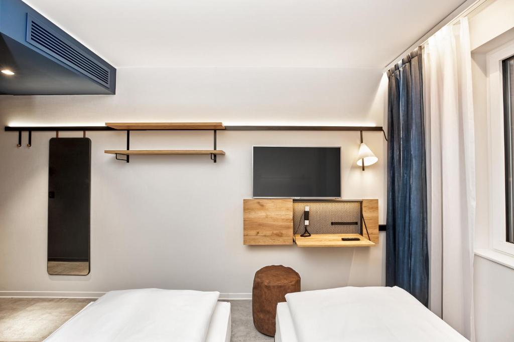 a room with two beds and a flat screen tv at H2 Hotel München Olympiapark in Munich