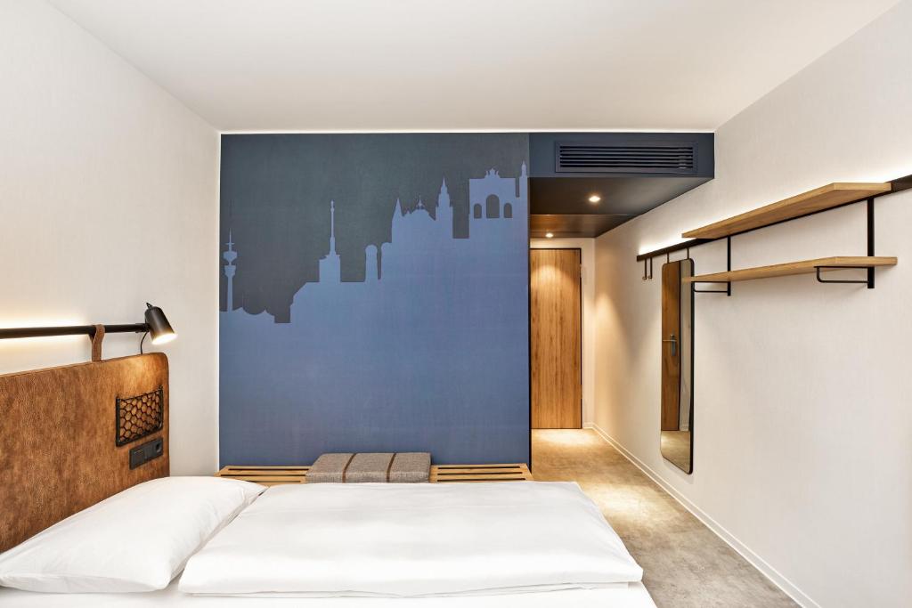 a bedroom with a bed and a blue wall at H2 Hotel München Olympiapark in Munich