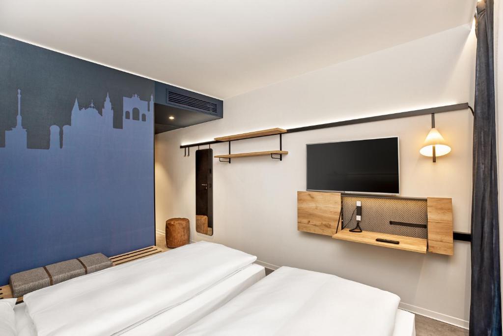 a hotel room with two beds and a flat screen tv at H2 Hotel München Olympiapark in Munich