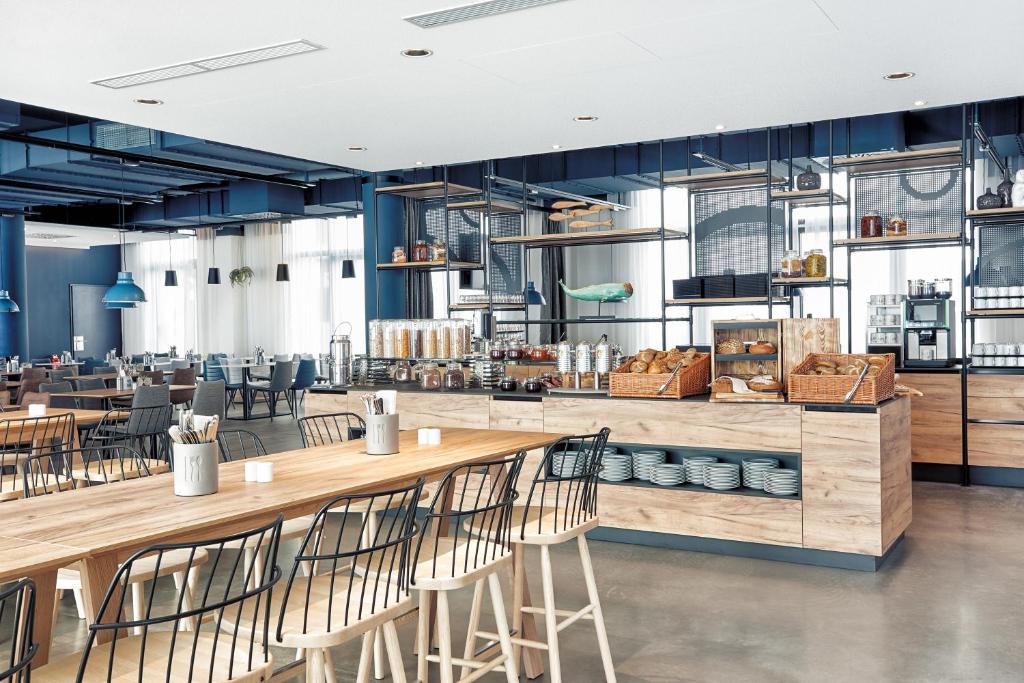 a restaurant with wooden tables and chairs at H2 Hotel München Olympiapark in Munich