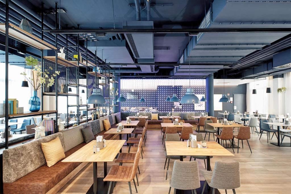 a restaurant with wooden tables and chairs at H2 Hotel München Olympiapark in Munich