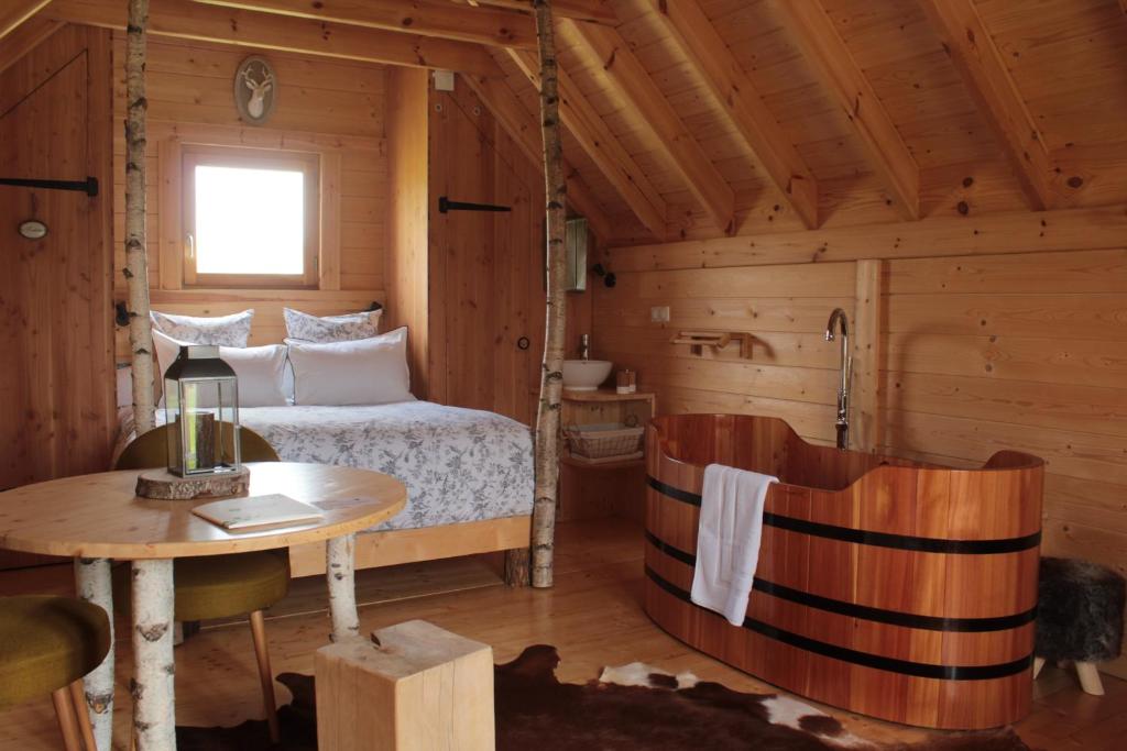 1 dormitorio en una cabaña de madera con 1 cama y 1 mesa en Shanti Lac Cabanes gîtes insolites et espace bien-être Bordeaux, en Berson