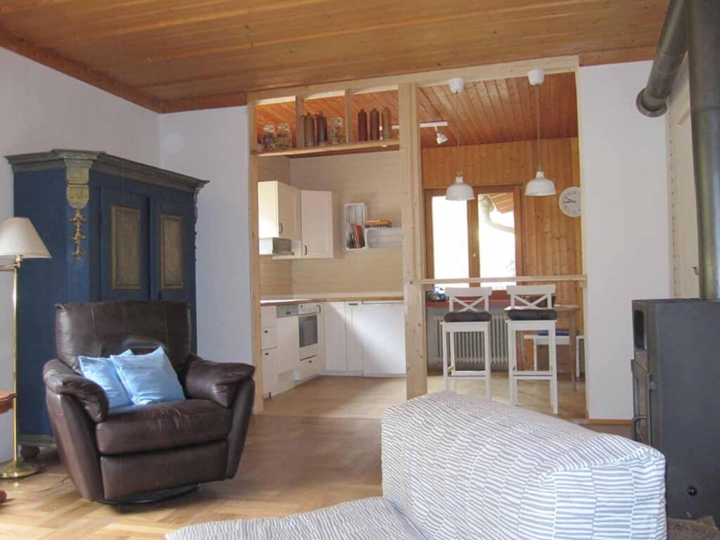 a living room with a chair and a kitchen at Ferienwohnungen Blätterrausch in Schwandorf in Bayern