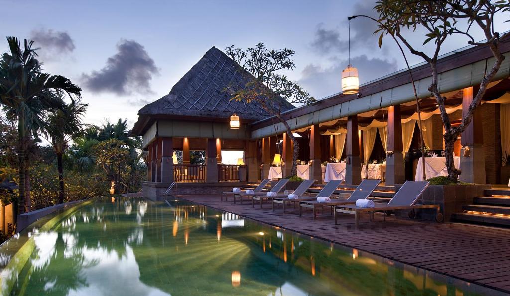 a resort with a swimming pool and lounge chairs at The Kayana in Seminyak