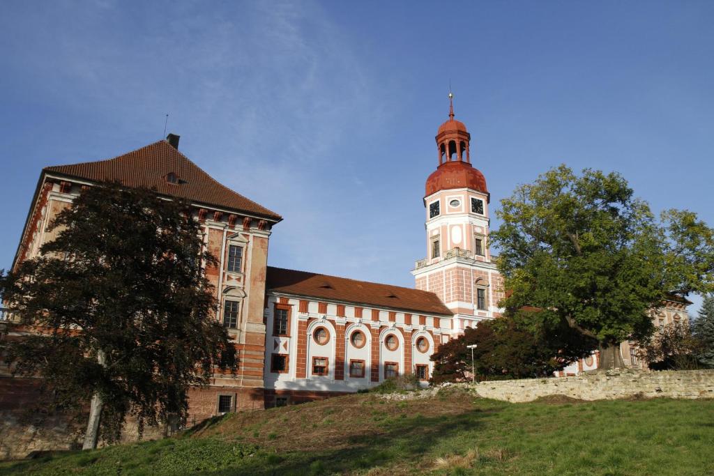 duży budynek z wieżą na szczycie wzgórza w obiekcie Apartmán pod rozhlednou w mieście Roudnice nad Labem