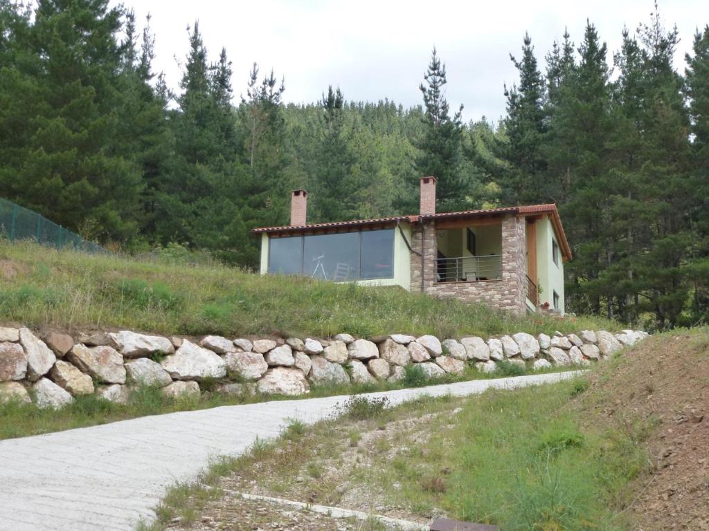 una casa en una colina con una pared de piedra en La Riega del Peral, en Ojedo