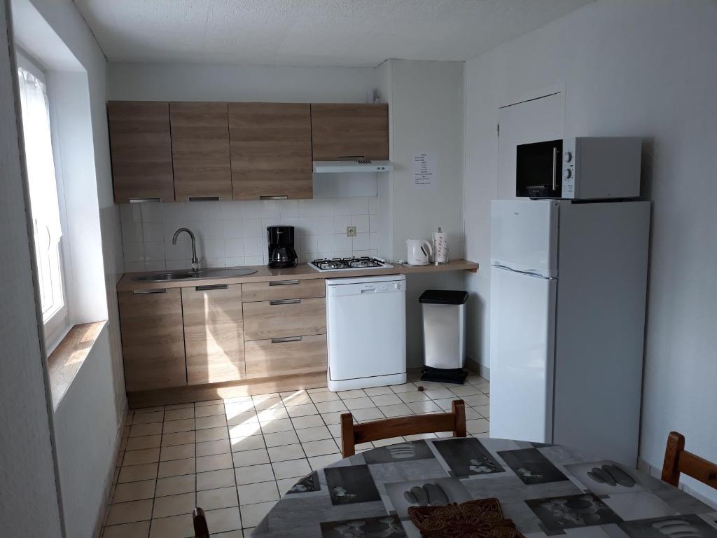 a kitchen with a white refrigerator and wooden cabinets at Appartement OMAHA BEACH in Saint-Laurent-sur-Mer