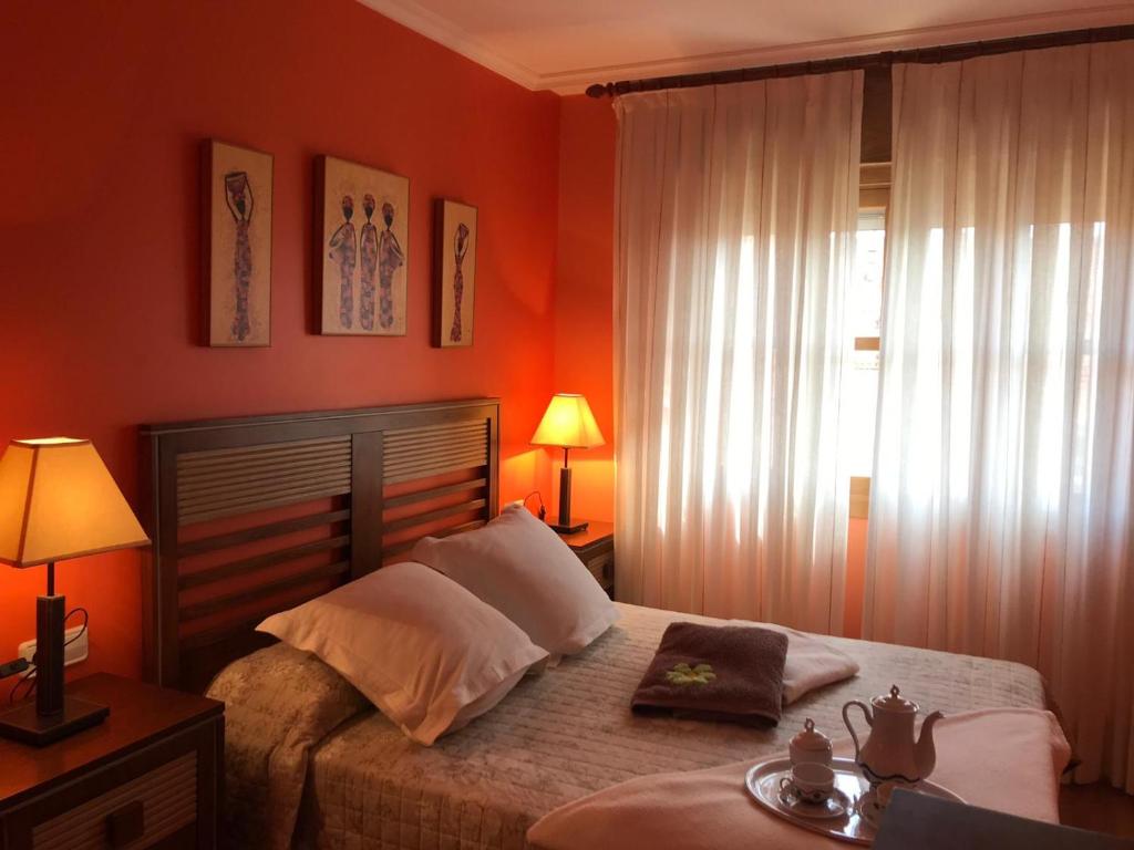 1 dormitorio con paredes de color naranja, 1 cama y ventana en APARTARMENTOS A D´MARIA, en Sanxenxo