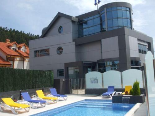 a building with chairs and a swimming pool in front of it at La Traina in Argoños