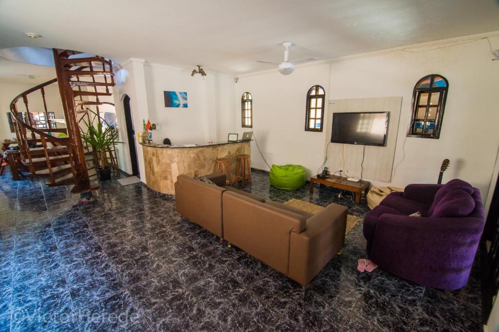 a living room with a couch and a tv at Kionda Surf House in Bertioga