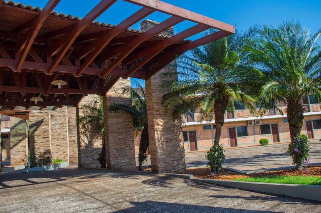 a patio with palm trees and a building at Vancouver Hotel- 500 Metros Rodovia Anhanguera in Ribeirão Preto