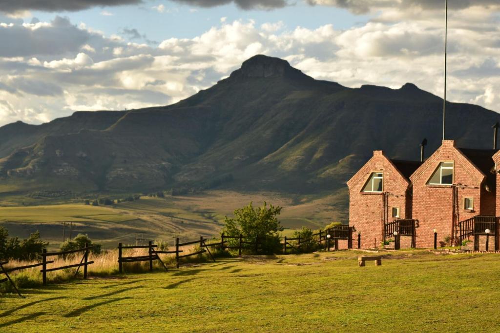 a house in a field with a mountain in the background at De Ark Mountain Lodge in Clarens