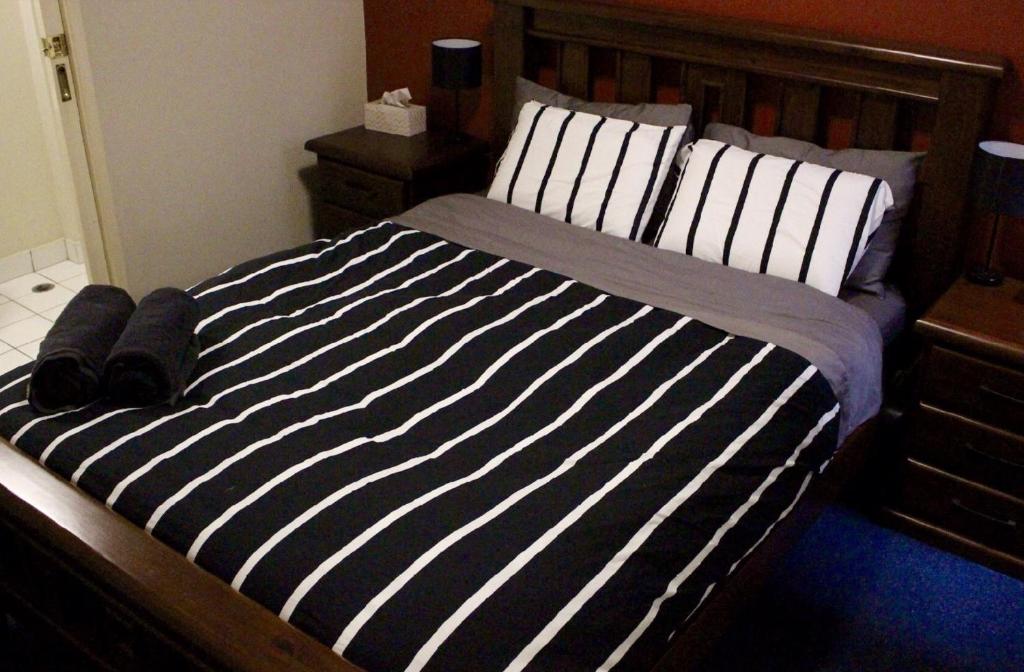 a bed with black and white striped sheets and pillows at Cosy City Apartment in Melbourne