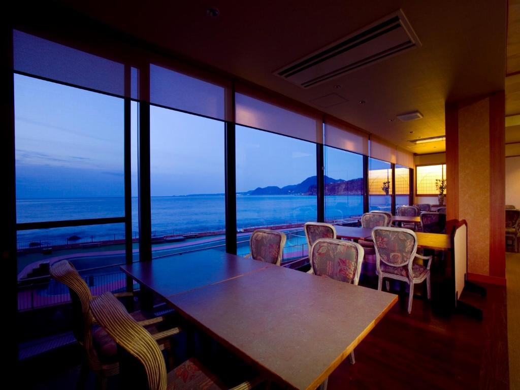 a dining room with tables and chairs and a view of the ocean at Inatori Tokai Hotel Yuen in Higashiizu