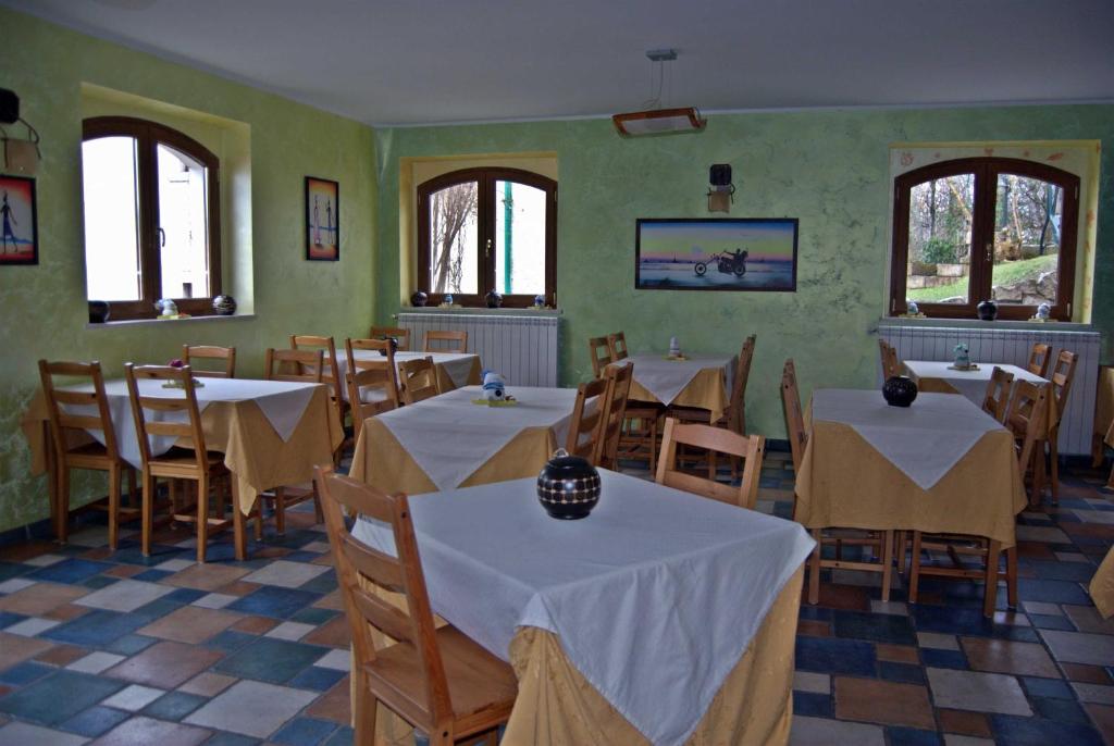 jadalnia ze stołami, krzesłami i oknami w obiekcie Casa Hotel Civitella w mieście Civitella Alfedena