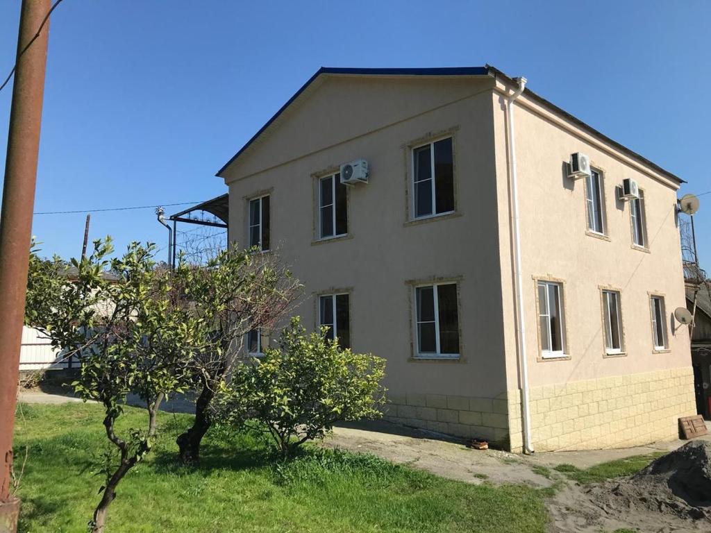 a large white house sitting on top of a field at Guest House San Tina in Gagra