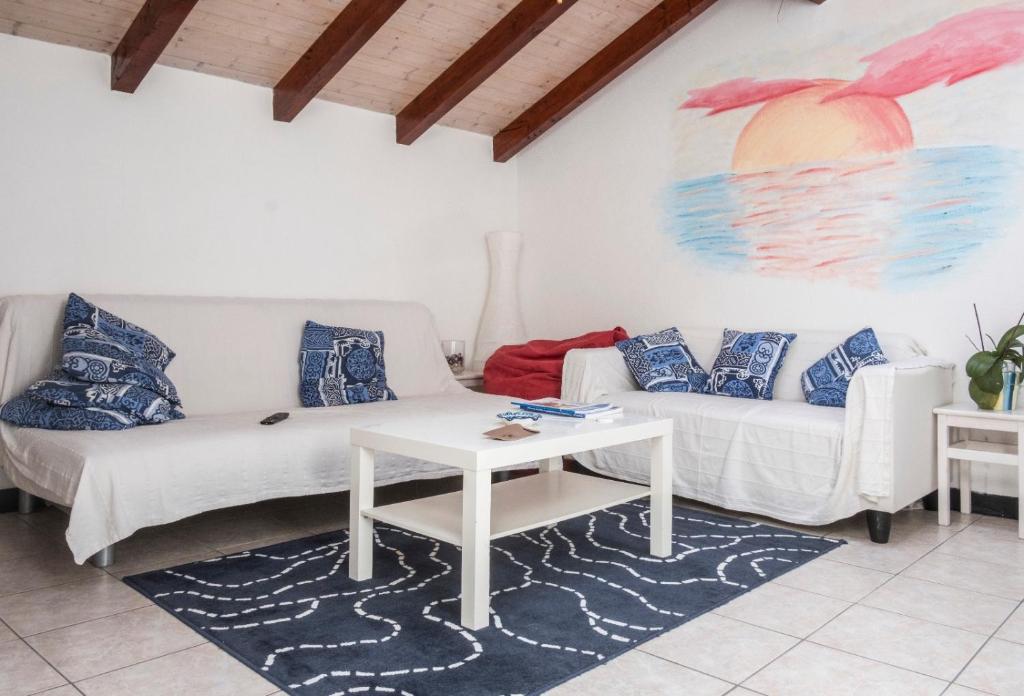 una sala de estar con 2 sofás blancos y una mesa. en Casa Helios, en Albenga