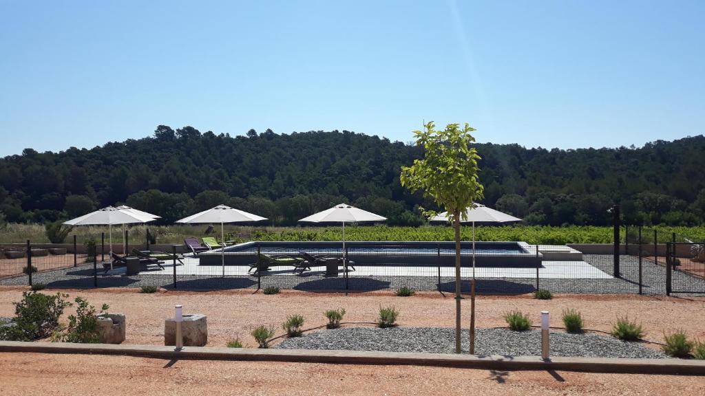 a picnic area with tables and umbrellas in a park at Sous Les Pins gîtes et chambres d'hôtes in La Londe-les-Maures
