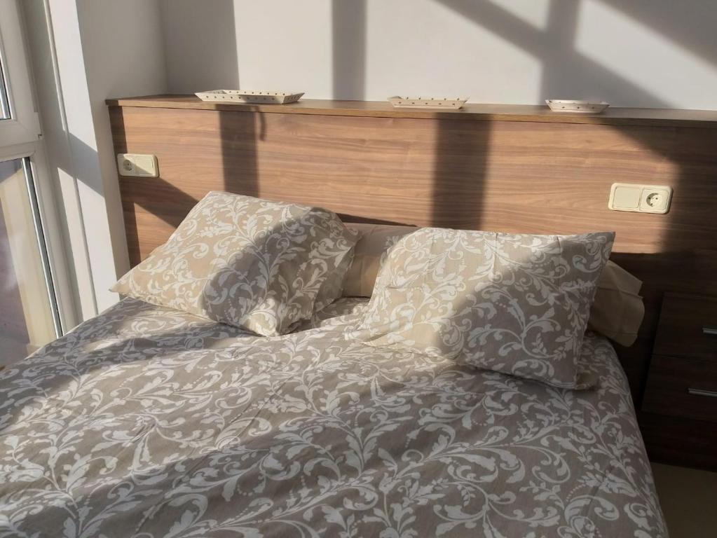 a bed with a wooden headboard and two pillows at Apartamento en Ribeira(centro) 1*planta in Ribeira