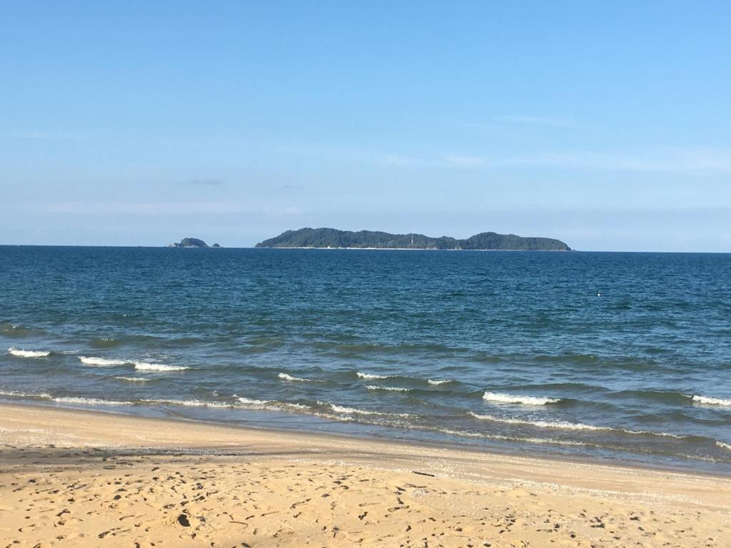 an empty beach with an island in the ocean at Zara Homestay in Marang